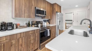 A modern kitchen with wooden cabinets, stainless steel appliances, and a white countertop.