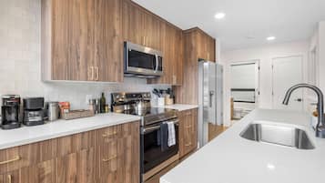 A modern kitchen with wooden cabinets, stainless steel appliances, and a white countertop.