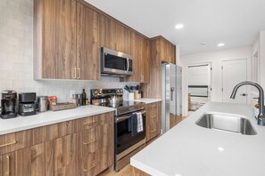 A modern kitchen with wooden cabinets, stainless steel appliances, and a white countertop.