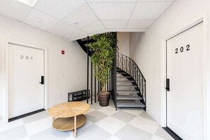 A hallway with a staircase, a potted plant, and a round table.