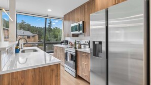 Eine moderne Küche mit Holzausstattung, Edelstahlgeräten und einem großen Fenster mit Blick ins Freie.