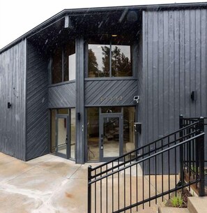 A modern building with a two-story entrance, large glass doors, and a metal staircase.