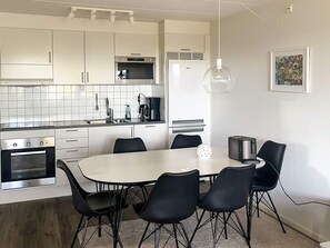 A modern kitchen with white cabinets, a microwave, a coffee maker, and a dining table with chairs. - 4 Star Holiday Home in Uddevalla (Uddevalla)