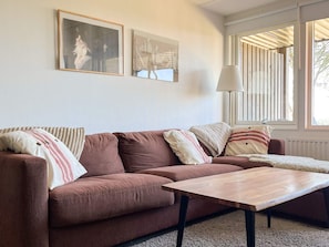 A living room with a brown sofa, a wooden coffee table, and two framed pictures on the wall. - 4 Star Holiday Home in Uddevalla (Uddevalla)