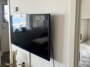 A flat-screen TV mounted on a textured wall, a door with a handle, and a bed with white bedding. - 4 Star Holiday Home in Uddevalla (Uddevalla)