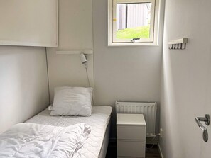 A small, single-bed room with a window, a radiator, and a bedside table. - 4 Star Holiday Home in Uddevalla (Uddevalla)