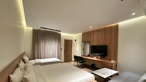 Ein modernes Hotelzimmer mit einem großen Bett, einem Schreibtisch, einem Flachbildfernseher und einer Sitzecke.