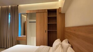 Ein Hotelzimmer mit einem Bett, einem Holzschrank, einem Spiegel und einem Vorhangfenster.