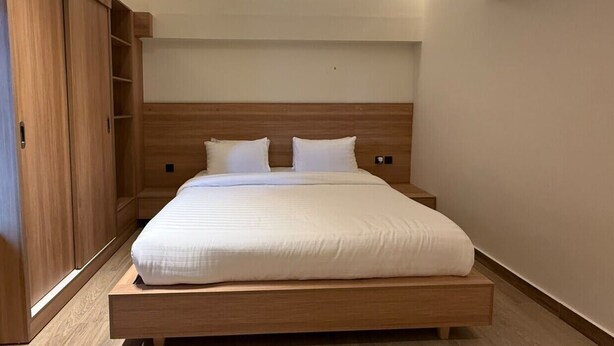 Ein Schlafzimmer mit hölzernem Bettgestell, einem eingebauten Kleiderschrank und einer Klimaanlage.