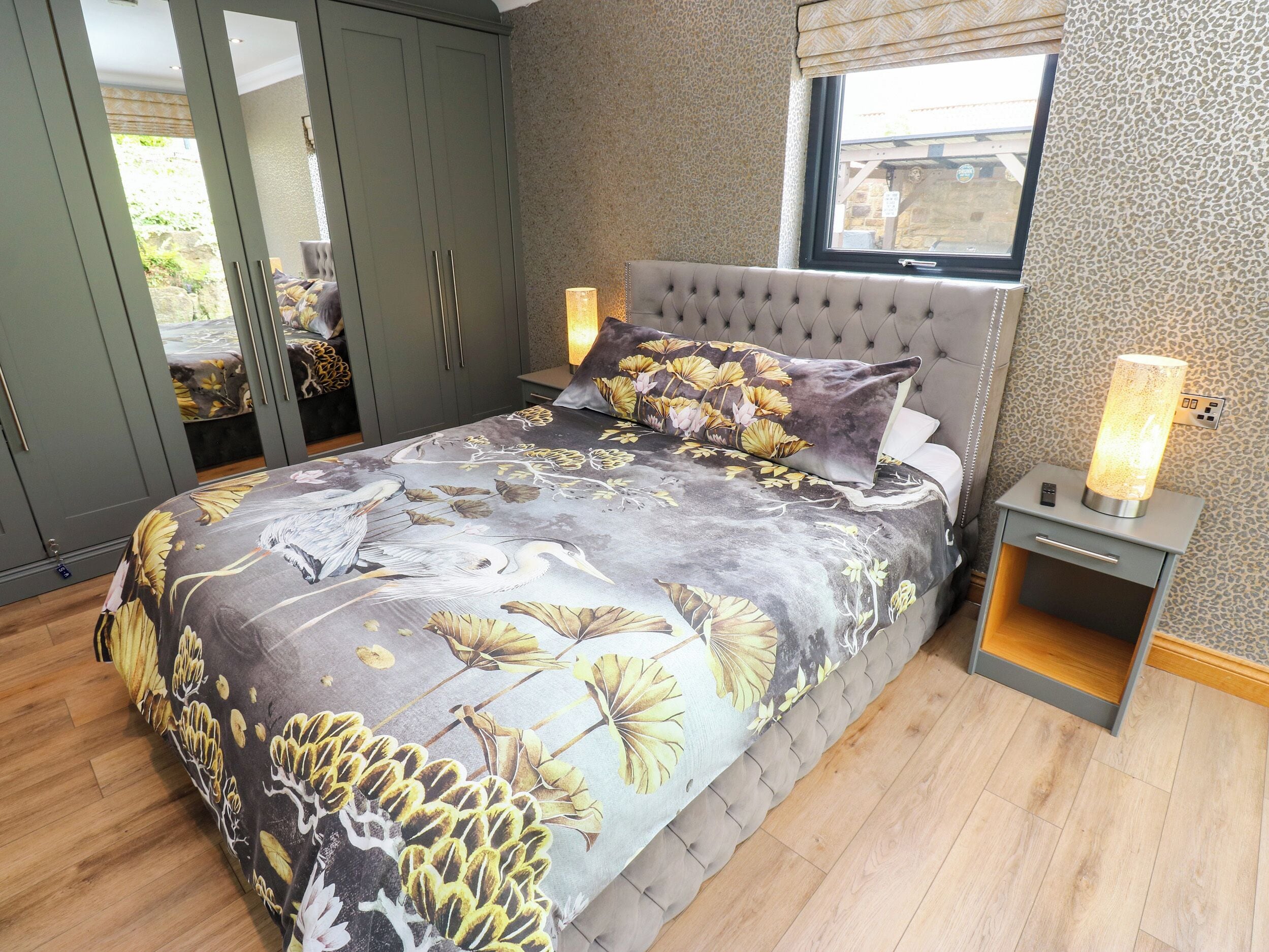 Un dormitorio con cama, mesita de noche, lámpara, armario y ventana.