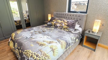 Un dormitorio con cama, mesita de noche, lámpara, armario y ventana.