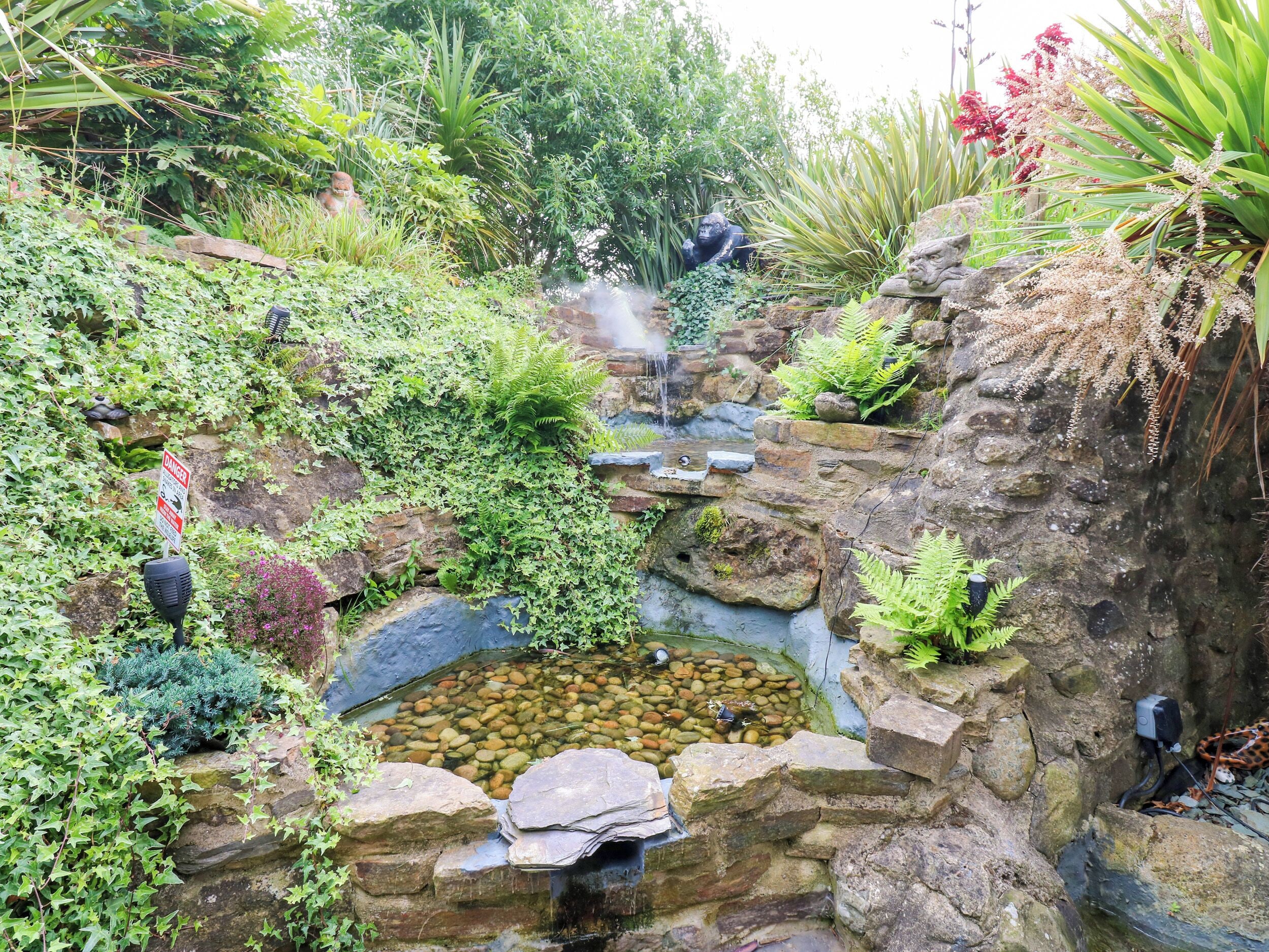 A garden with a water feature, rocks, and various plants.