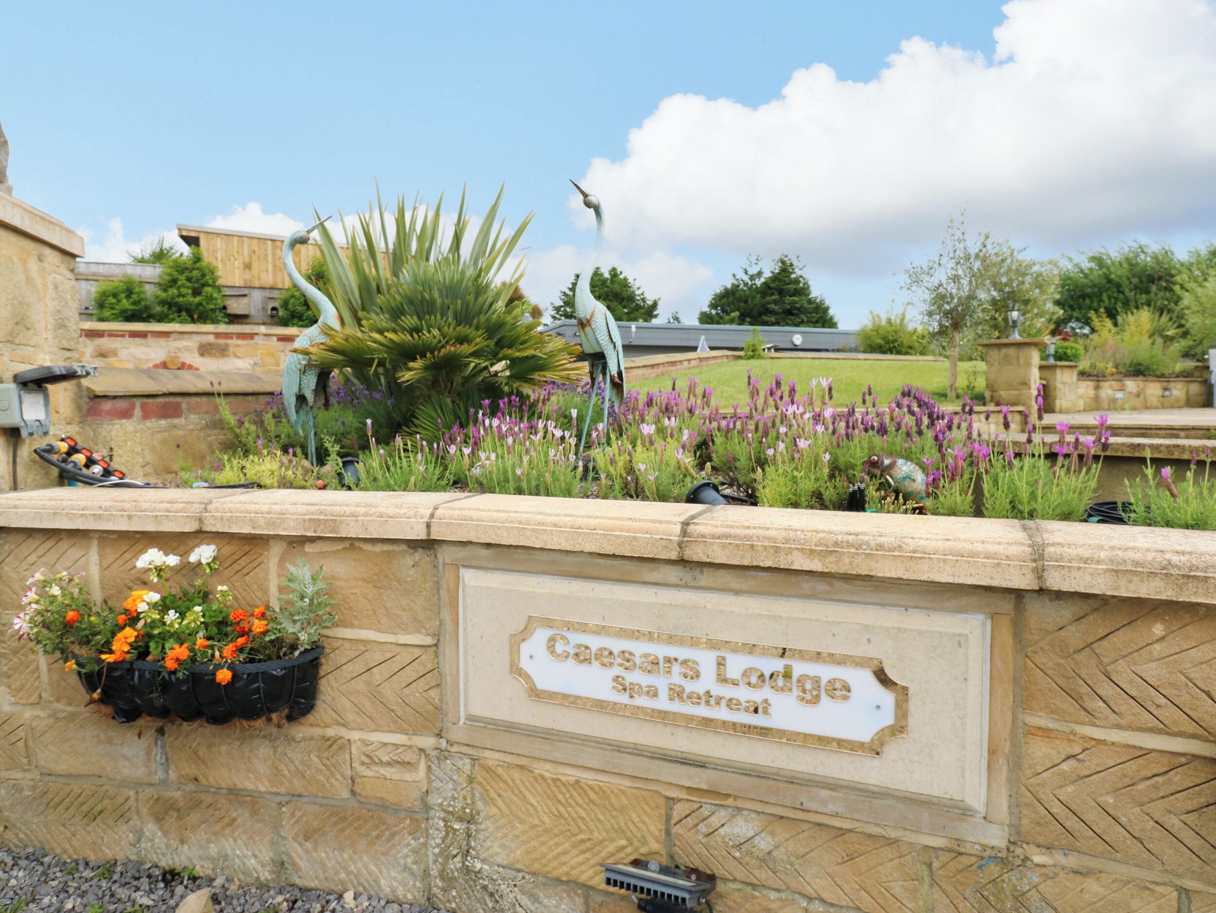 A stone wall with a sign for Caesars Lodge Spa Retreat.