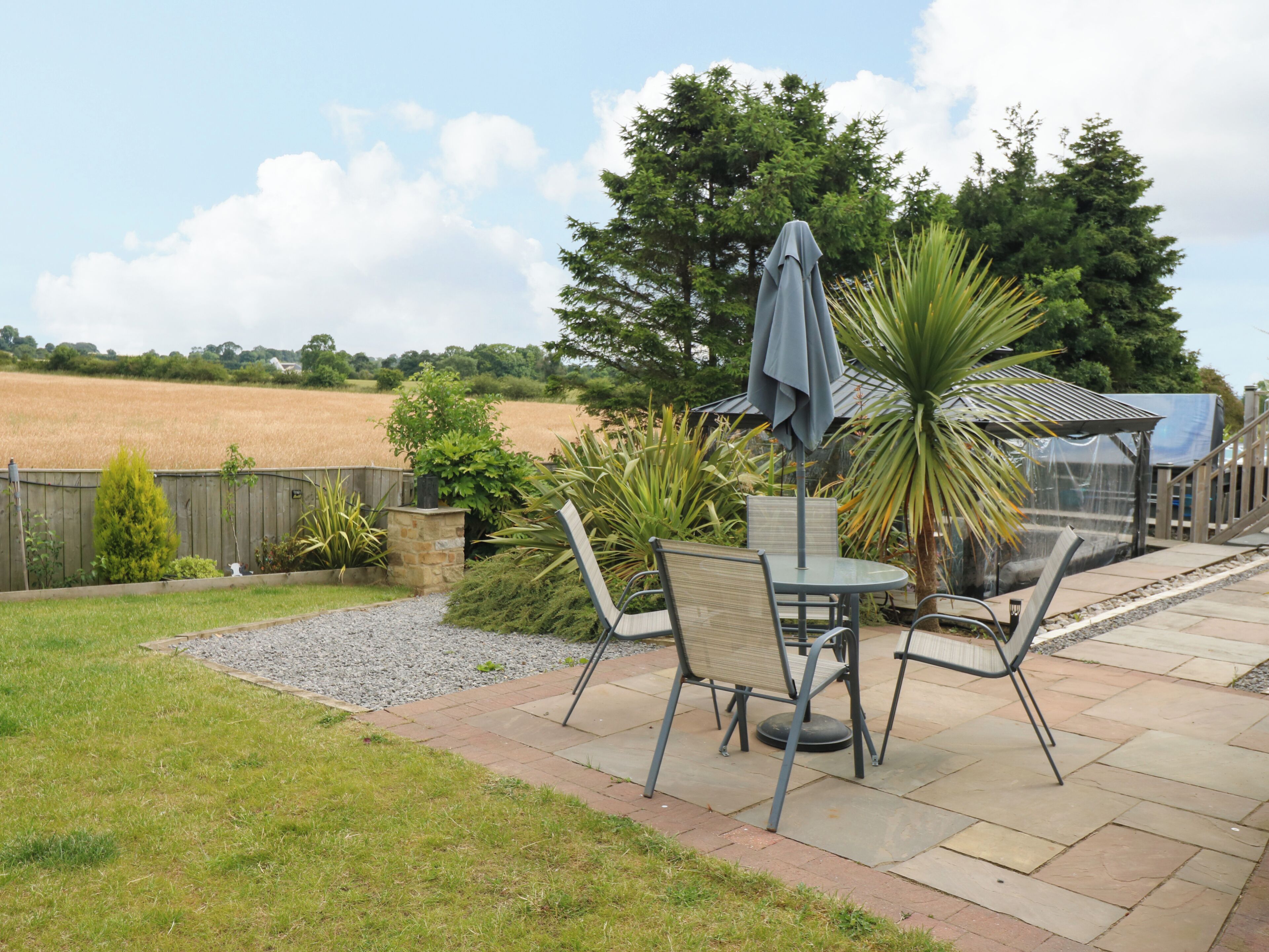 A patio with a table and chairs, a covered seating area, and a view of a field.
