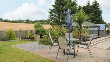 A patio with a table and chairs, a covered seating area, and a view of a field.