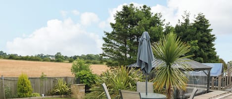 A patio with a table and chairs, a covered seating area, and a view of a field.