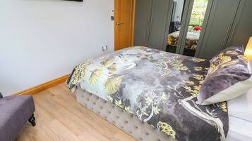 Ein Schlafzimmer mit einem Bett, einer Holztür, einem Kleiderschrank und einem Fernseher an der Wand.