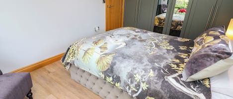 Un dormitorio con cama, una puerta de madera, un armario y un televisor en la pared.