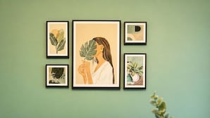 Un soggiorno con un divano grigio, cuscini a righe, un tavolino da caffè in legno e opere d'arte botaniche incorniciate al muro.