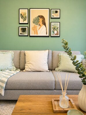 A living room with a grey sofa, striped pillows, a wooden coffee table, and framed botanical artwork on the wall. - Cozy stay in city centre with free parking (Edinburgh)