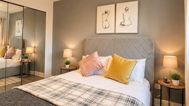 Una camera da letto moderna con un letto grande, comodini, uno specchio e opere d'arte alle pareti.