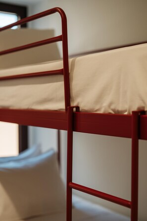 Un lit superposé avec une structure en métal rouge et une literie beige.