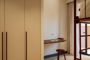 Une pièce comprenant un lit, un bureau, une chaise et une fenêtre avec des rideaux.