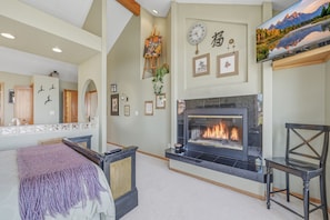 A room with a fireplace, framed pictures, a clock, and a television. - Panoramic Ocean Views, Grill, Wraparound Decks (Pacific City)