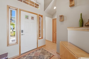 A hallway with a white door, a small window, and a wooden bench. - Panoramic Ocean Views, Grill, Wraparound Decks (Pacific City)