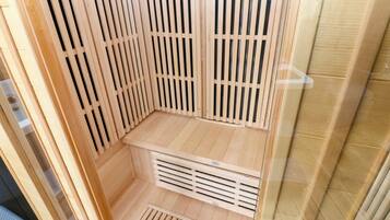 A sauna room with wooden slats, a bench, and a vent.