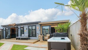 Un patio moderno al aire libre con jacuzzi, zona de estar y un pequeño jardín.