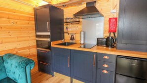 Una cocina compacta con armarios oscuros, una campana extractora negra y un horno empotrado.