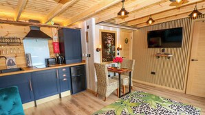 Una cocina compacta con electrodomésticos modernos, un comedor con mesa y sillas, y una zona de estar acogedora con un tapete estampado.