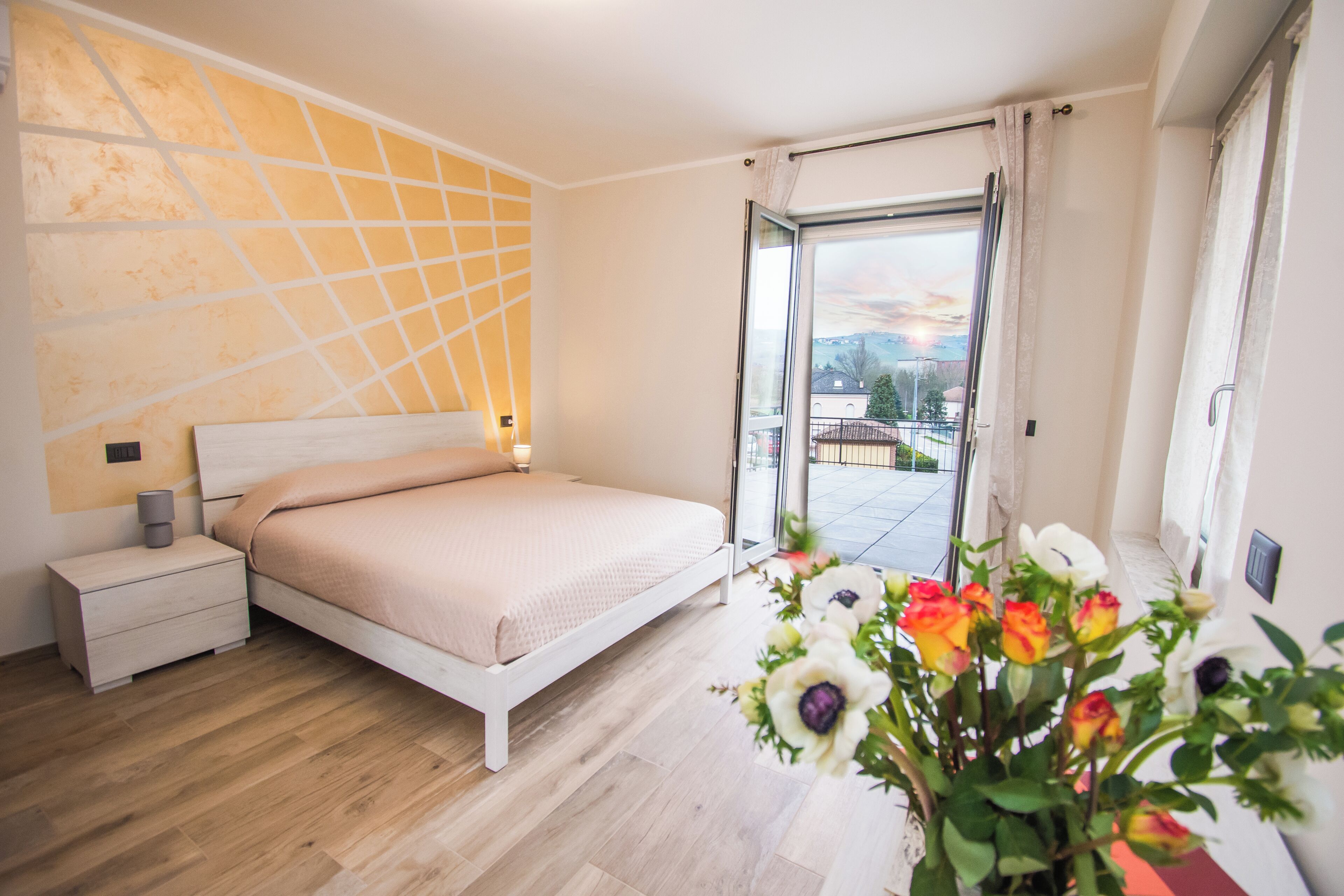 A bedroom with a bed, bedside table, and a view of the outside.