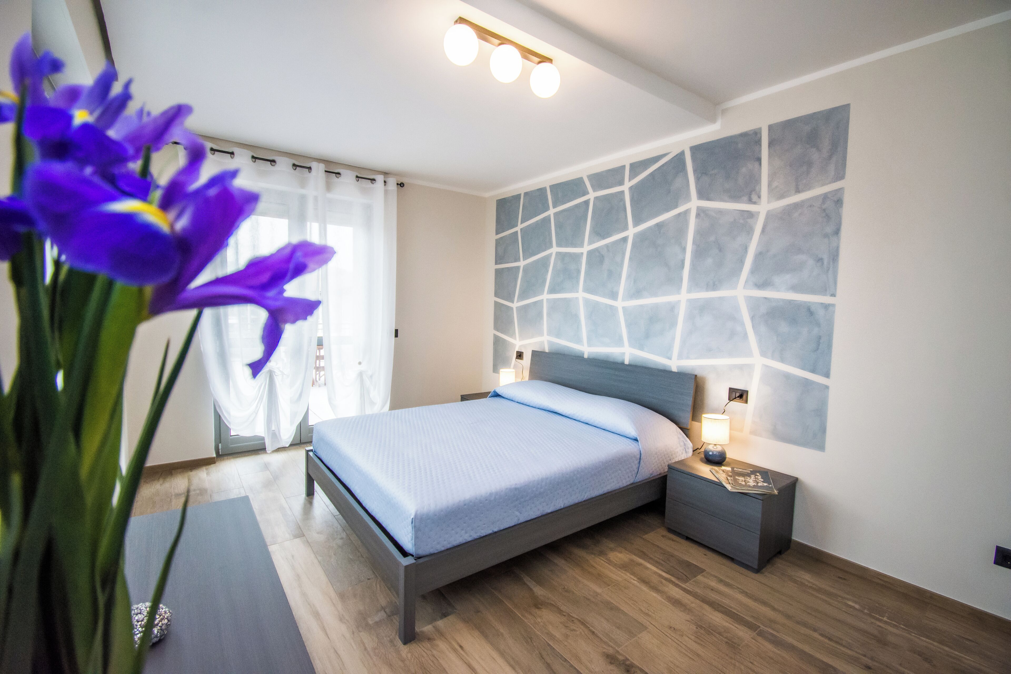 Un dormitorio moderno con una cama, una mesita de noche y una lámpara de pared.