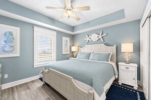 A bedroom with a bed, ceiling fan, artwork, and a nightstand. - stunning Gulf views, resort-style amenities, and an unbeatable location (Panama City Beach)