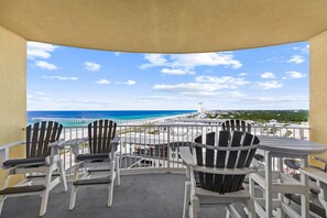 Un balcón con vistas a la playa, sillas y una mesa.