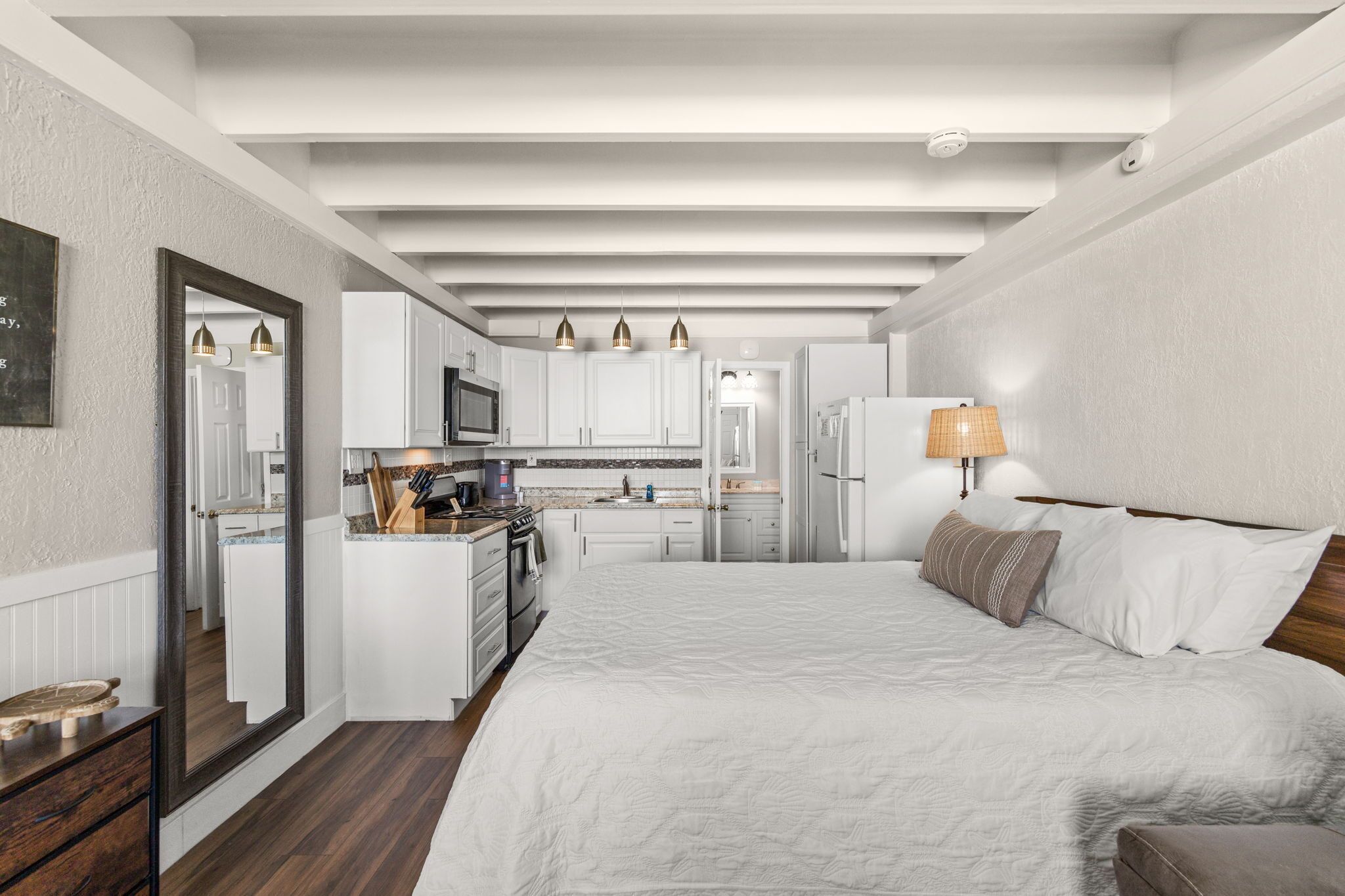 Un dormitorio moderno con una cama grande, una mesita de noche y una lámpara.