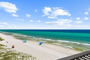 A beach with a clear sky, calm sea, and a few beach umbrellas. - Beachfront Studio at Fontainebleau | Private Beach Access (Panama City Beach)