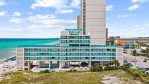 Ein Hotel mit mehreren Etagen, Blick auf den Strand und einem Parkplatz.