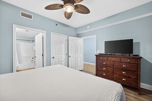A bedroom with a bed, a dresser, a television, and a ceiling fan. - Coastal Comfort with Gulf Views at Laketown Wharf 1416 (Panama City Beach)