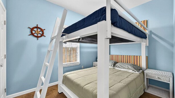 Habitación con literas, una decoración de timón de barco, una ventana con persianas y un cabecero a rayas.