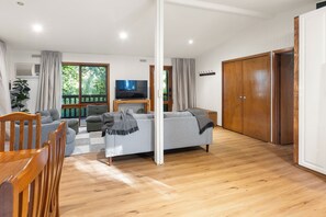 A modern living room with a grey sofa, wooden chairs, a flat-screen TV, and a large wooden wardrobe. - Diamond Lodge: 3  BR, 1  BA House in Sawmill Settlement, Sleeps 8 (Sawmill Settlement)