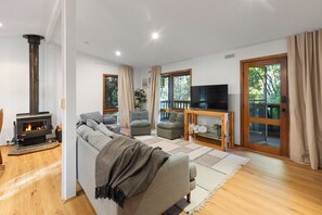 A modern living room with a fireplace, comfortable seating, a television, and a view of the outdoors. - Diamond Lodge: 3  BR, 1  BA House in Sawmill Settlement, Sleeps 8 (Sawmill Settlement)