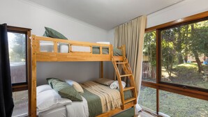 Ein Stockbett mit einer Leiter, ein Fenster mit Vorhängen und Blick ins Freie.