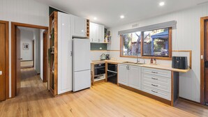 A modern kitchen with white cabinets, wooden flooring, and a built-in oven.