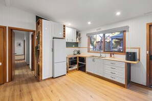 A modern kitchen with white cabinets, wooden flooring, and a built-in oven. - Diamond Lodge: 3  BR, 1  BA House in Sawmill Settlement, Sleeps 8 (Sawmill Settlement)
