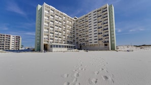 Ett hotell vid stranden med flera våningar, balkonger och en sandstrand framför.
