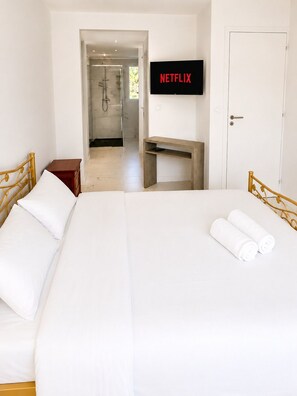 A hotel room with a bed, a desk, a shower area, and a TV mounted on the wall. - Haven of Peace (Gommenec'h)