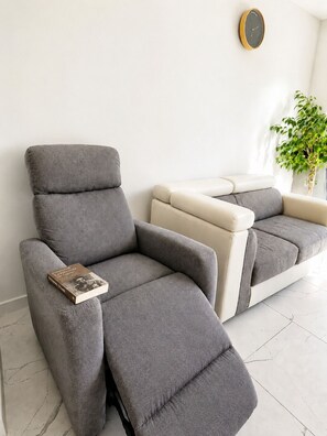 A modern living room with two grey sofas, a small table with a book, a wall clock, and a potted plant. - Haven of Peace (Gommenec'h)